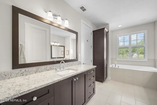 a bathroom with a granite countertop bathtub a sink and a large mirror