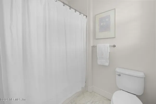 a bathroom with a granite countertop toilet a sink a mirror a shower a vanity and window