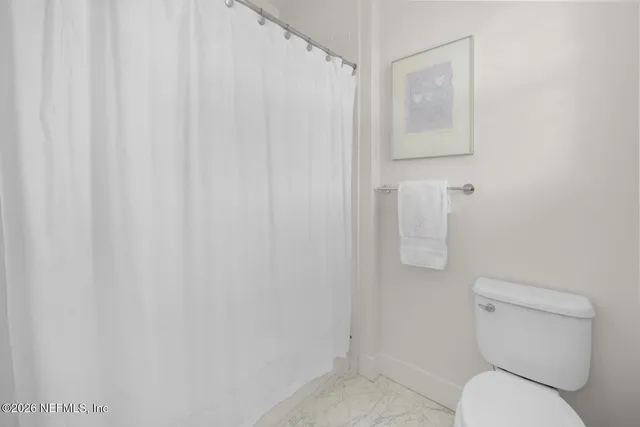 a bathroom with a granite countertop toilet a sink a mirror a shower a vanity and window