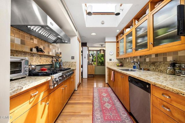 a large kitchen with stainless steel appliances granite countertop lots of counter top space and wooden floor