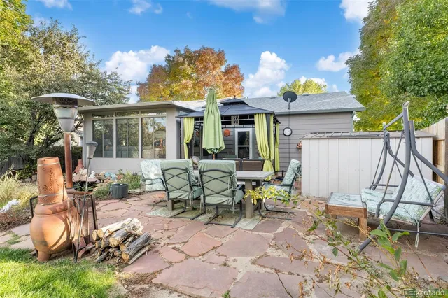 a view of a patio with table and chairs potted plants and large tree