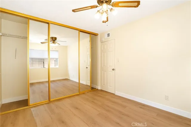 an empty room with a chandelier fan and wooden floor