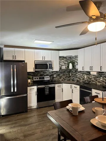 a kitchen with stainless steel appliances kitchen island granite countertop a sink dishwasher stove and refrigerator with wooden floor