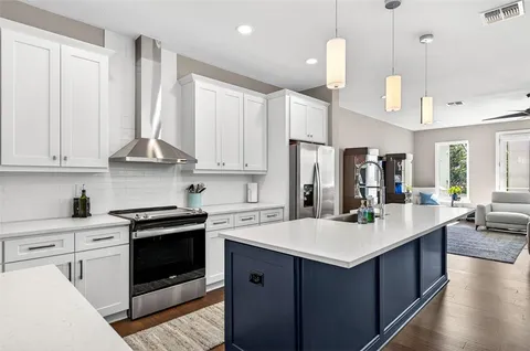 a kitchen with a sink dishwasher a stove a dining table and chairs with wooden floor