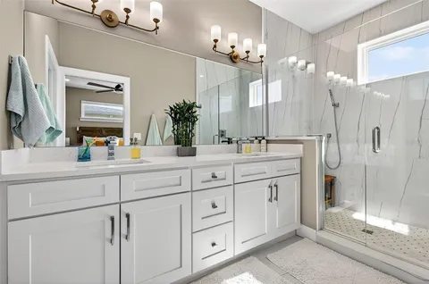 a bathroom with a double vanity sink mirror and shower