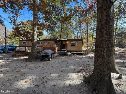 a view of a house with truck parked on a road near a forest