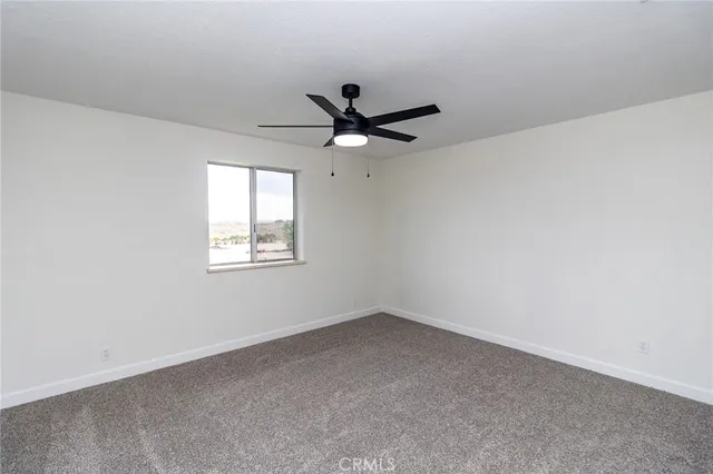 an empty room with ceiling fan and window