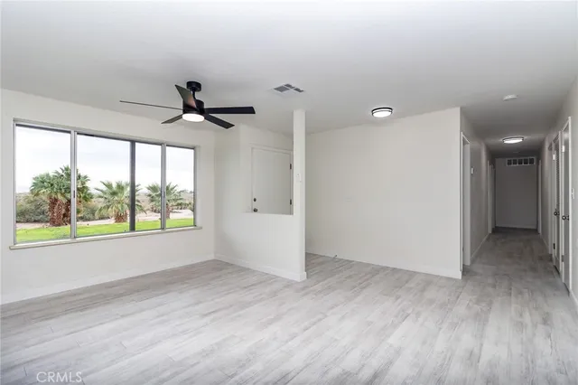 a view of an empty room with a window and wooden floor