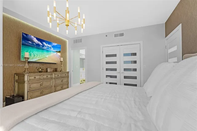 a spacious bedroom with a bed and a flat screen tv