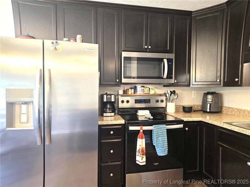 5345 Pittman Grove Church Road Raeford, NC 28376 - Photo 14 of 45 a kitchen with granite countertop a refrigerator and a stove top oven