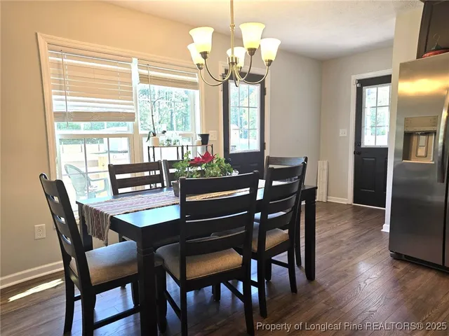 a dining room with wooden floor a chandelier a wooden table and chairs