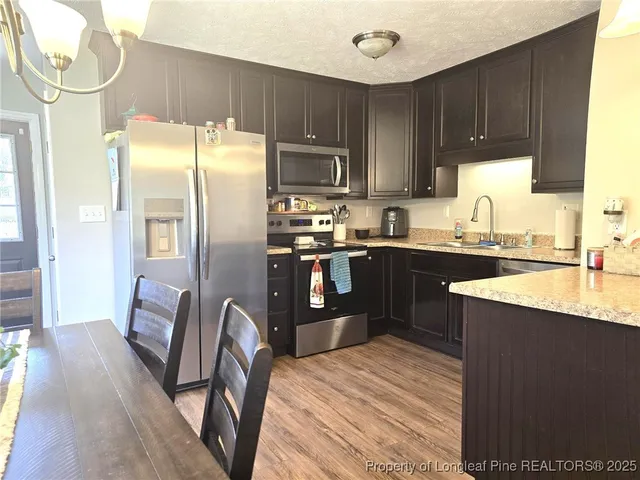 a kitchen with granite countertop a refrigerator stove top oven and sink