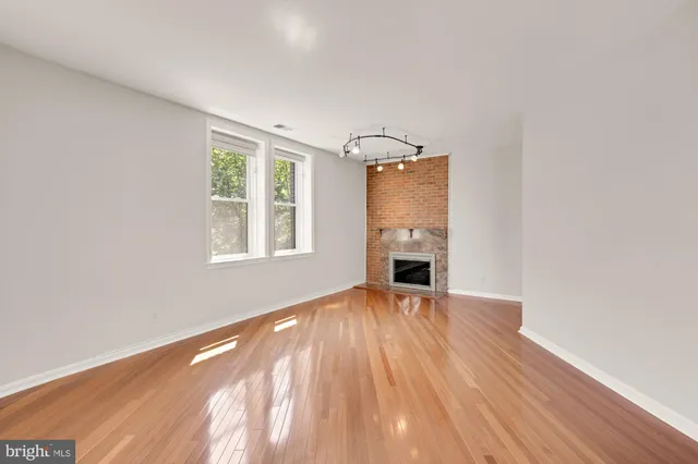 a view of empty room with wooden floor and fireplace
