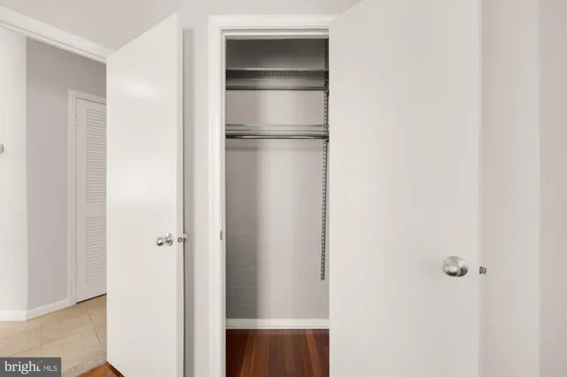 a walk in closet with wooden floor