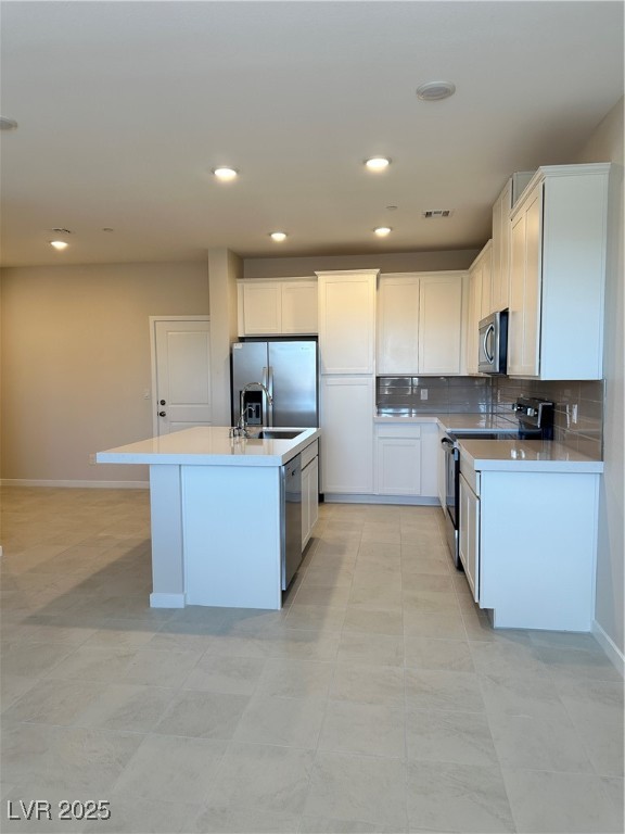 Undisclosed Address Henderson, NV 89011 - Photo 2 of 8 Kitchen featuring backsplash, stainless steel range oven, a center island with sink, paneled refrigerator, and white cabinets