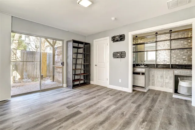a view of an empty room with a window and wooden floor