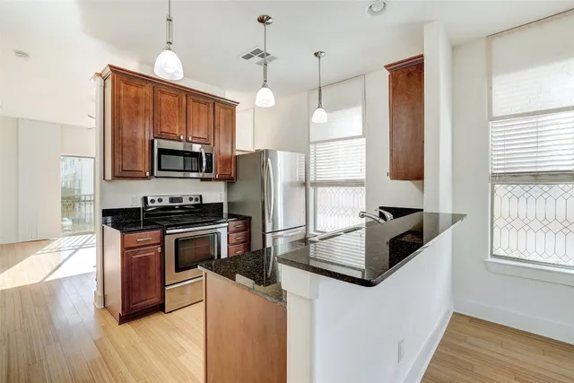 a kitchen with stainless steel appliances granite countertop a refrigerator a stove top oven a sink dishwasher and a refrigerator with wooden floor