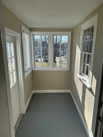 a view of an empty room with wooden floor and windows