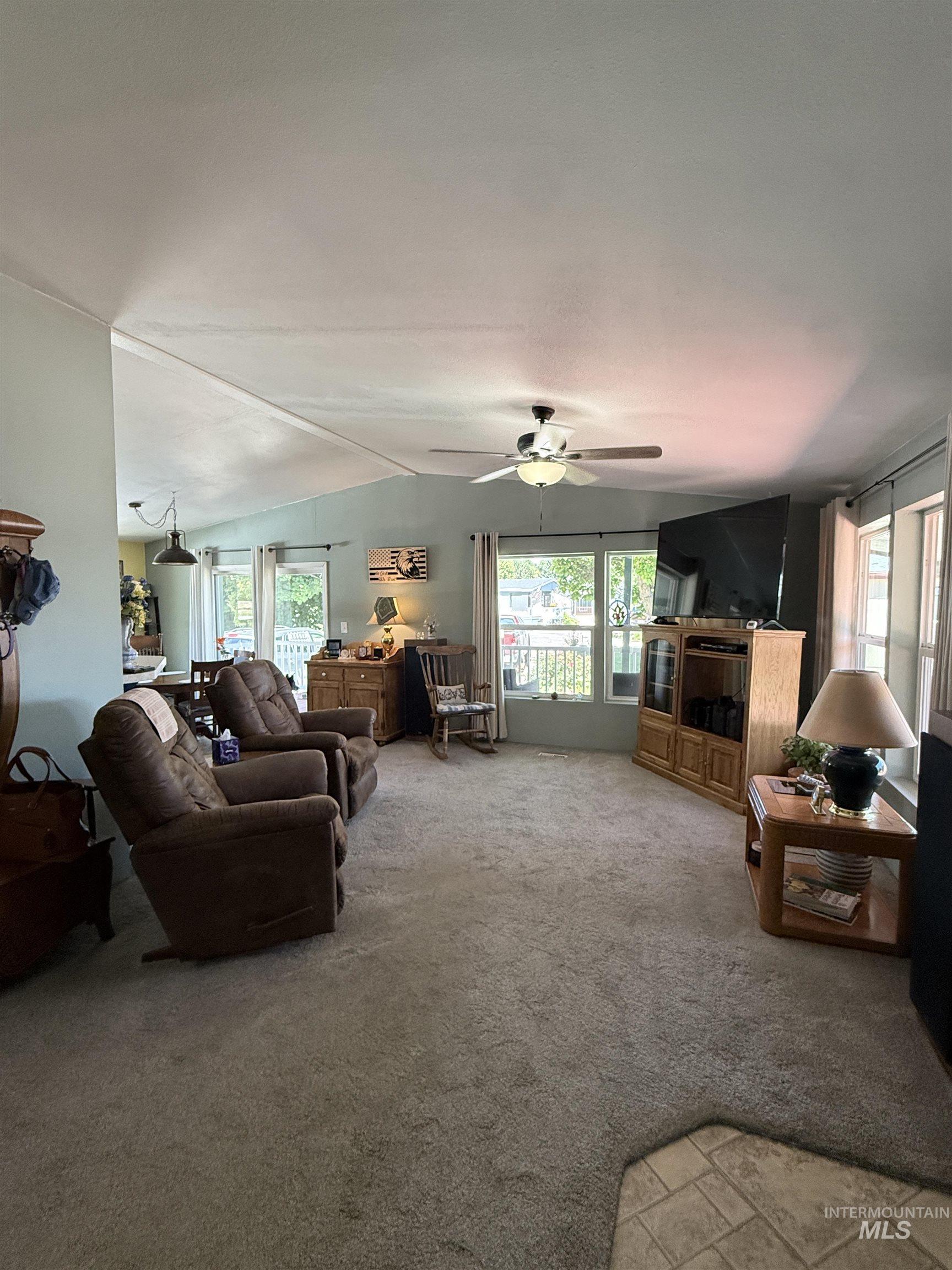 2750 Alden Road, Unit 12 12 Fruitland, ID 83619 - Photo 9 of 38 Spacious living area featuring vaulted ceilings, ceiling fan, carpet flooring, and abundant natural light from multiple windows