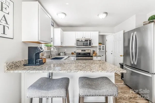 a kitchen with stainless steel appliances granite countertop a sink refrigerator and cabinets