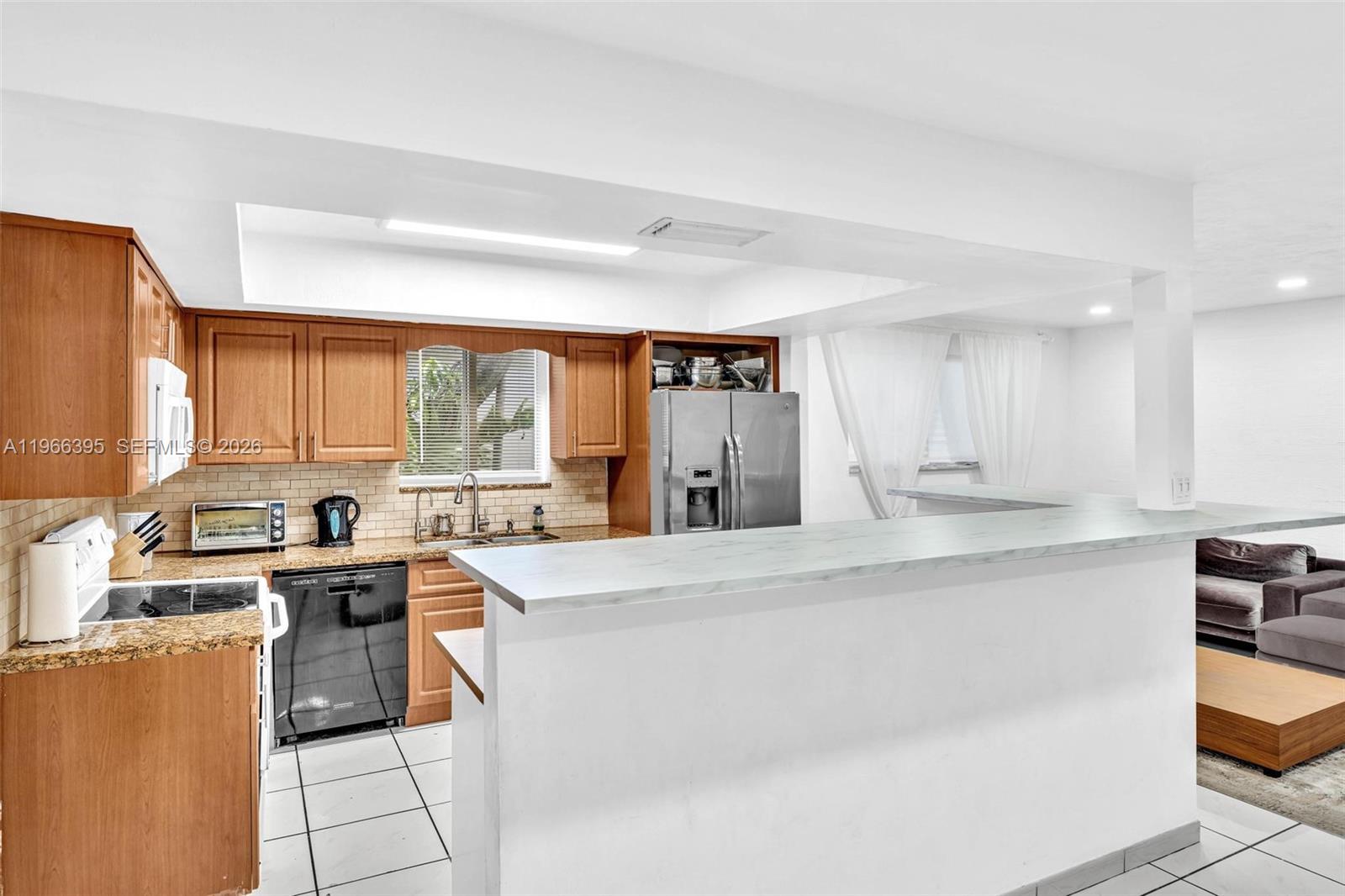 9524 Byron Avenue Surfside, FL 33154 - Photo 28 of 53 a kitchen with stainless steel appliances a sink a stove a refrigerator cabinets and a dining table with wooden floor