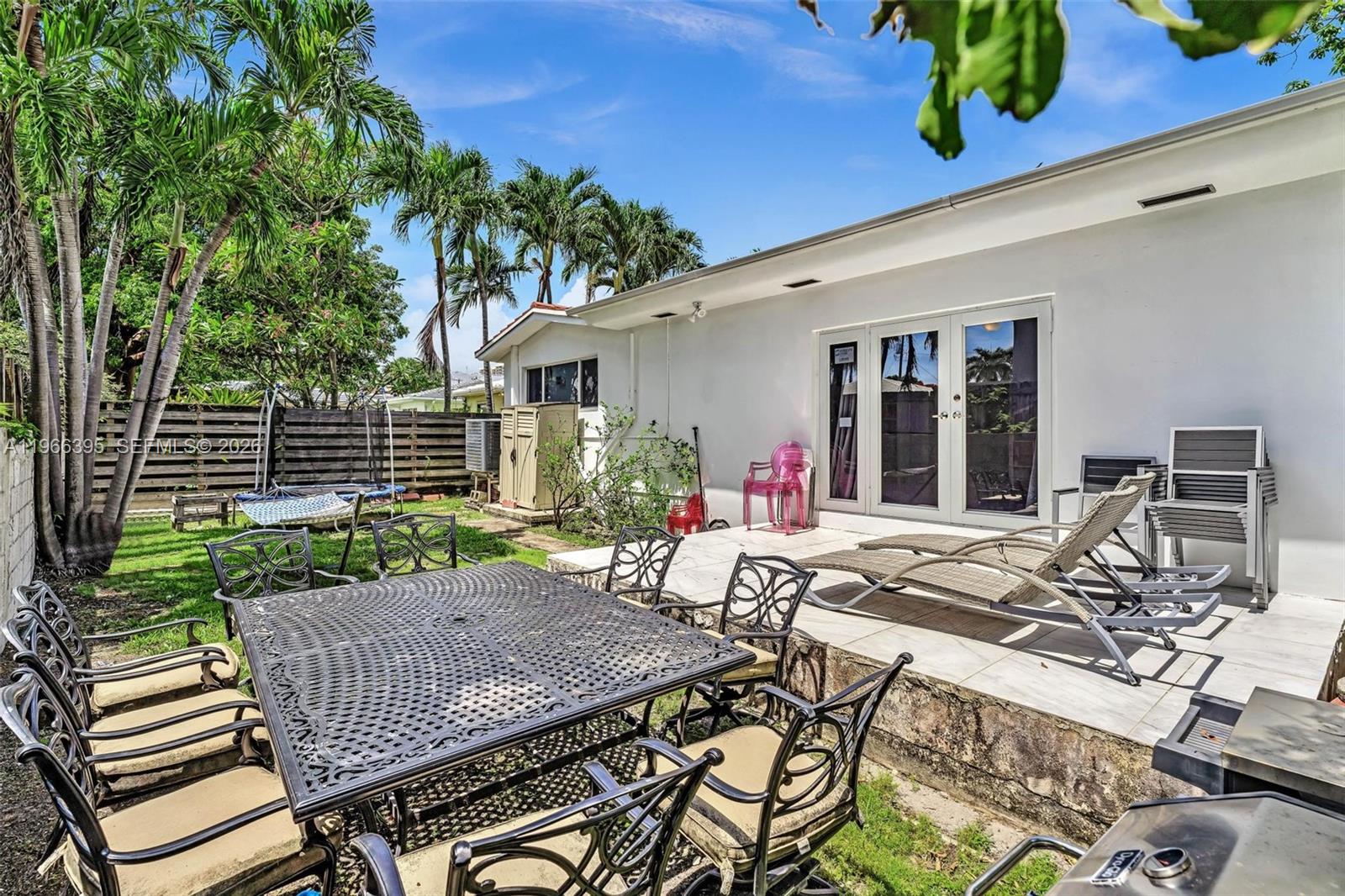 9524 Byron Avenue Surfside, FL 33154 - Photo 51 of 53 a view of a patio with table and chairs with wooden floor and plants