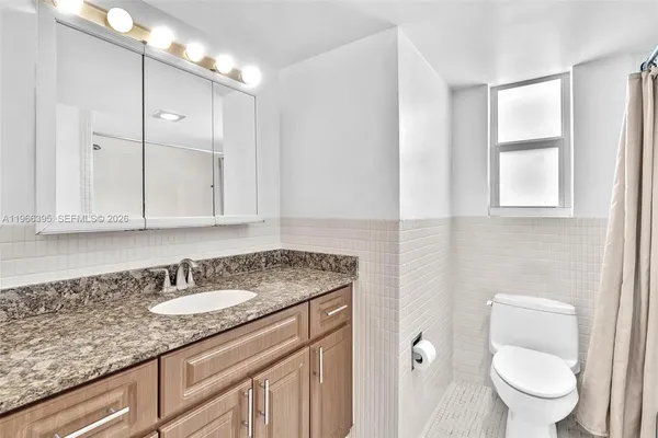 a spacious bathroom with a granite countertop sink a toilet and a bathtub