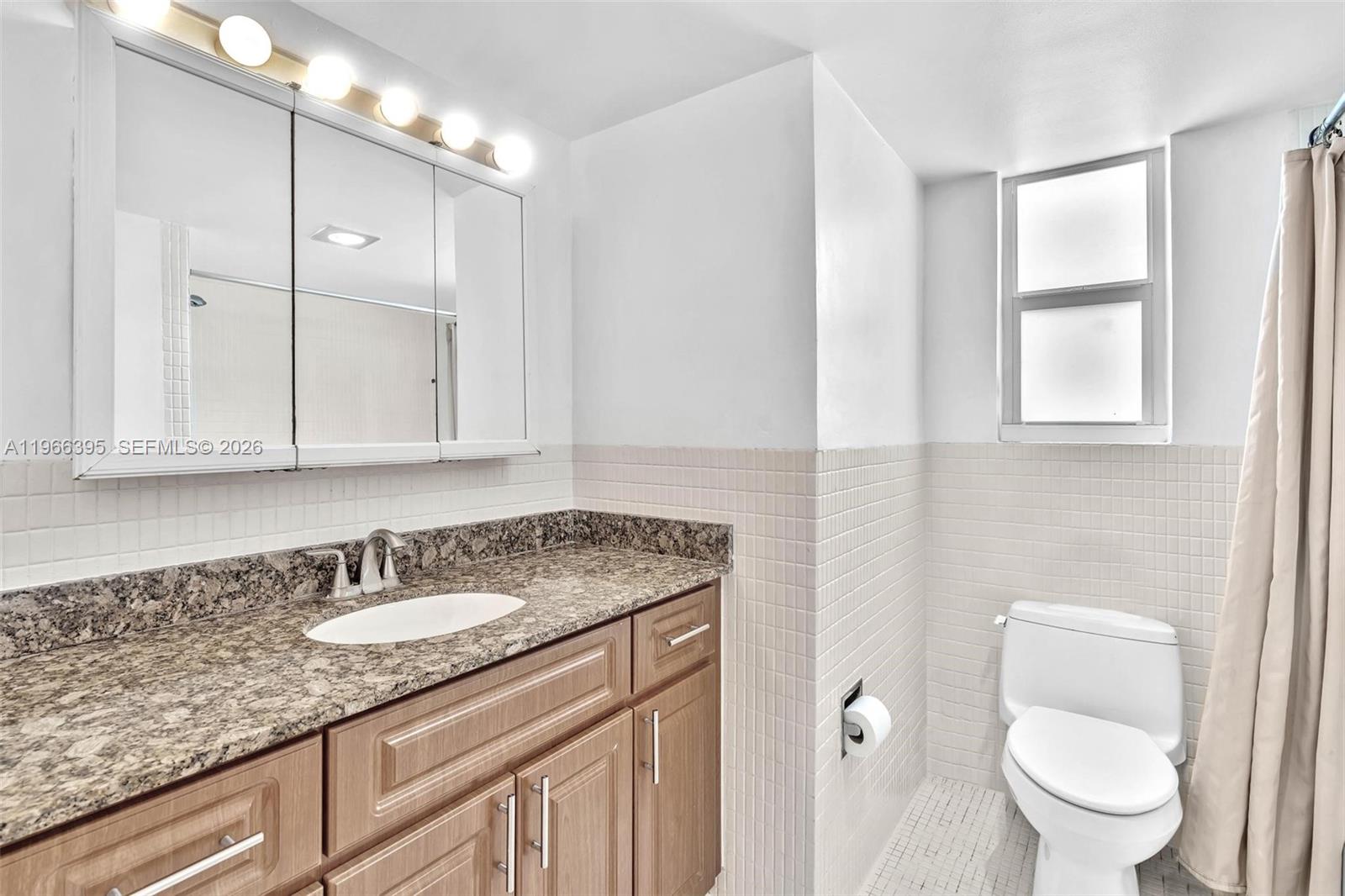 9524 Byron Avenue Surfside, FL 33154 - Photo 10 of 53 a bathroom with a granite countertop sink a toilet and a mirror