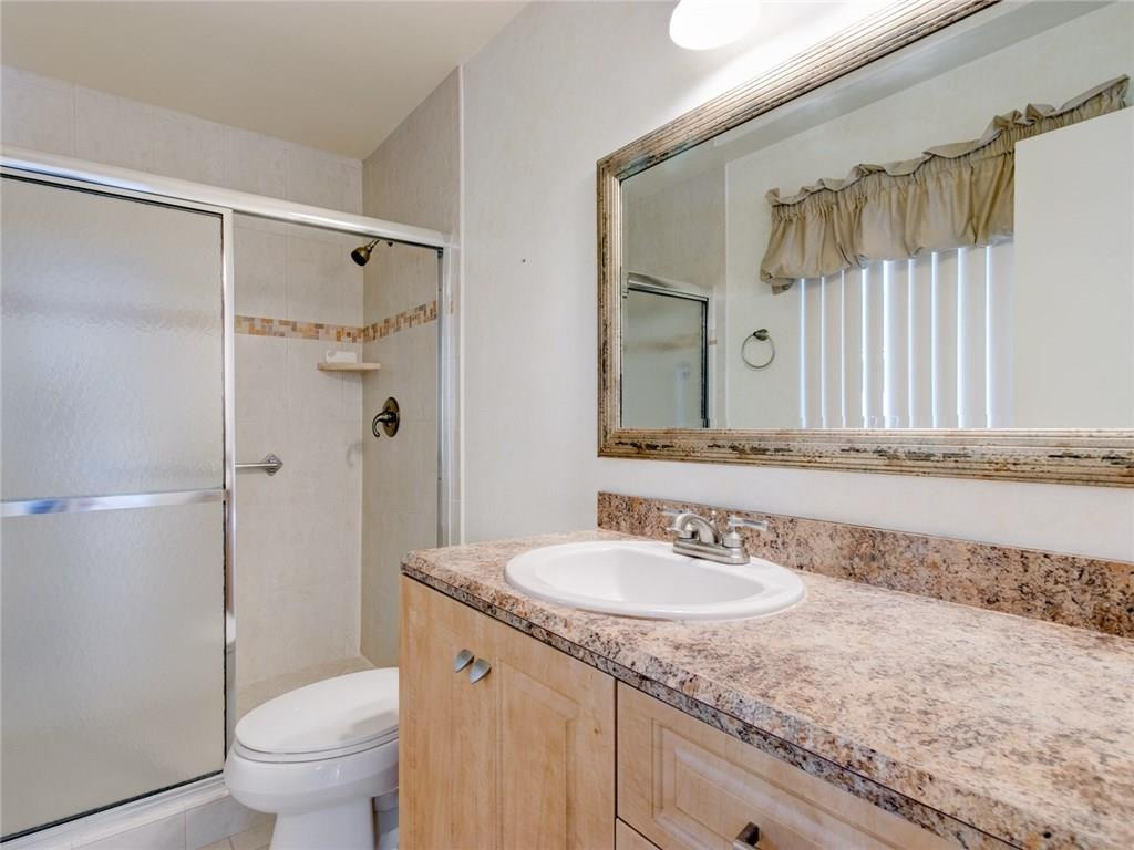 679 Racquet Club Road, Unit 4 Weston, FL 33326 - Photo 20 of 35 a bathroom with a granite countertop sink a toilet and a shower