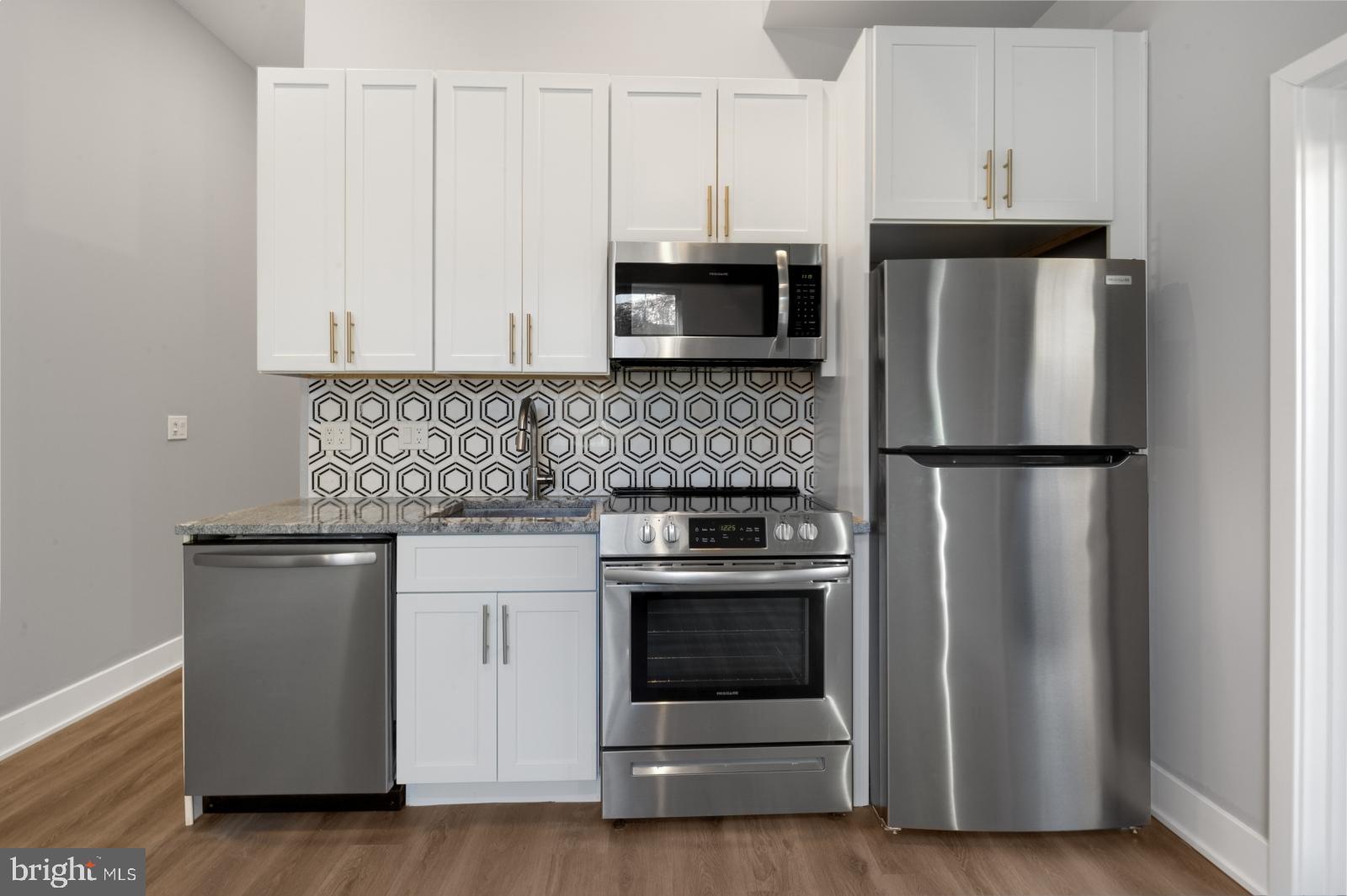 2119 North Front Street, Unit 101 Philadelphia, PA 19122 - Photo 7 of 23 a kitchen with granite countertop white cabinets and stainless steel appliances