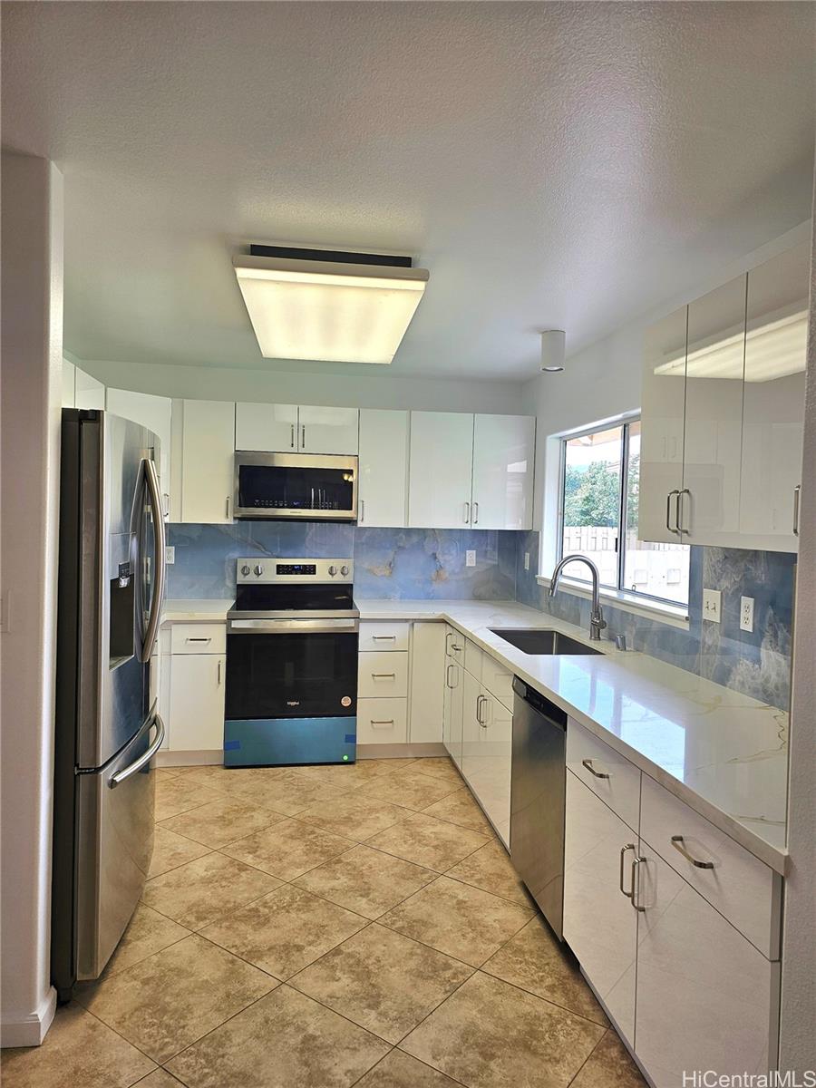 91-1040 Kanihaalilo Street Kapolei, HI 96707 - Photo 4 of 12 a kitchen with stainless steel appliances granite countertop a stove a sink and a refrigerator