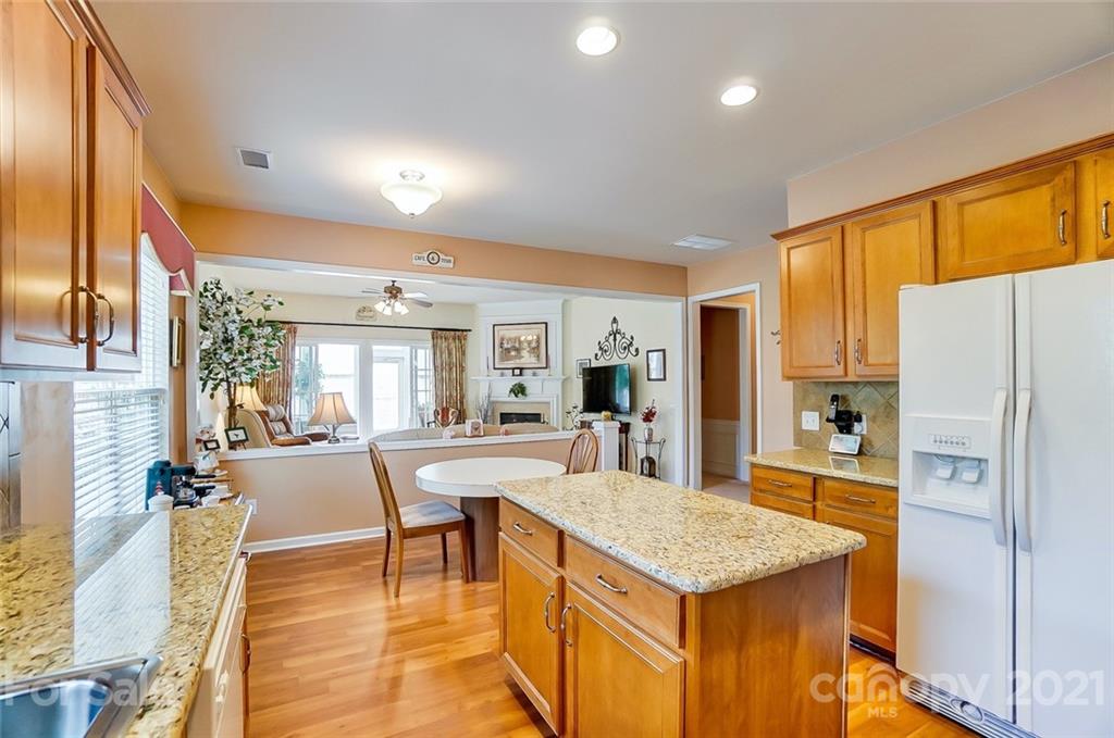 2135 Ashley River Road Waxhaw, NC 28173 - Photo 5 of 17 a kitchen with stainless steel appliances granite countertop a refrigerator a stove and a dining table with wooden floor