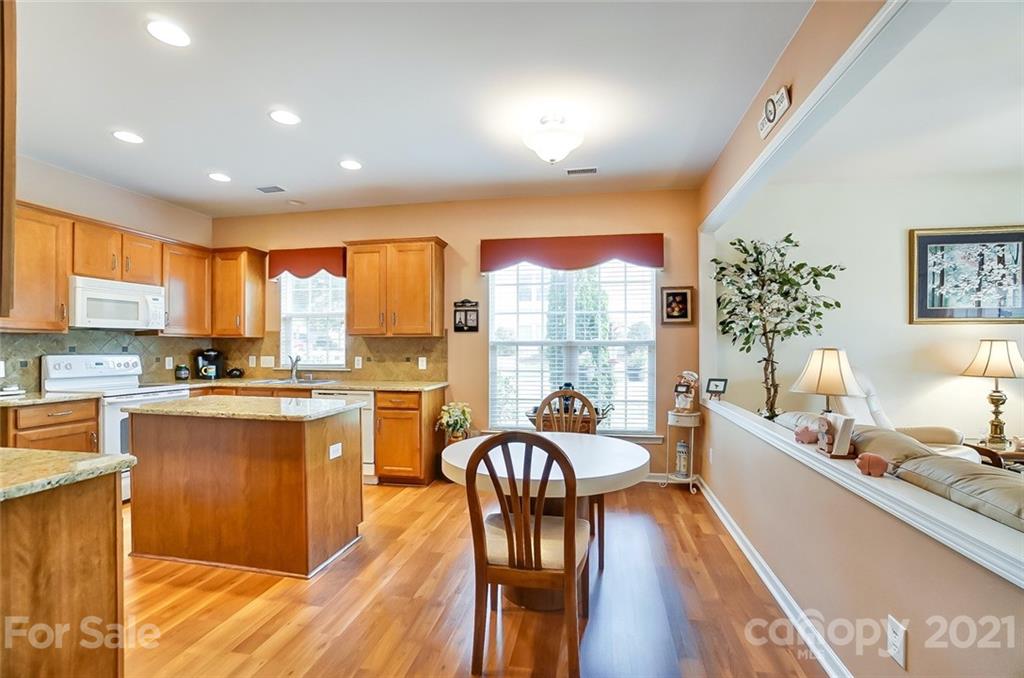 2135 Ashley River Road Waxhaw, NC 28173 - Photo 6 of 17 a kitchen with stainless steel appliances granite countertop a stove top oven a sink dishwasher a dining table and chairs with wooden floor