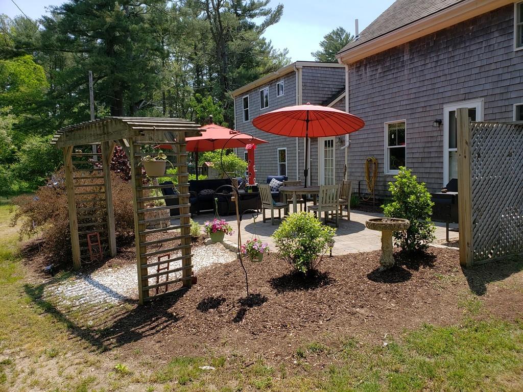 206 Blackmore Pond Road Wareham, MA 02576 - Photo 1 of 23 a view of a patio with couches table and chairs under an umbrella