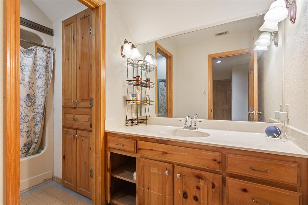 564 Sam Bass Road McGregor, TX 76657 - Photo 19 of 37 Bathroom featuring a single vanity with an integrated sink, light-toned countertop, and natural wood cabinetry