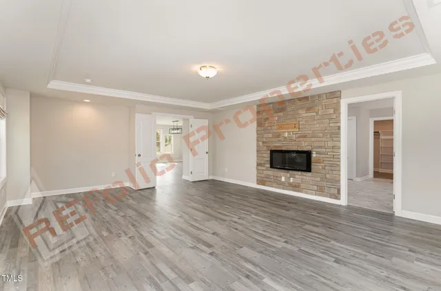 a view of an empty room with wooden floor fireplace and a window