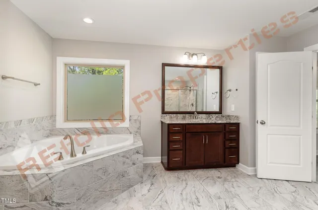 a bathroom with a tub a sink and a large window