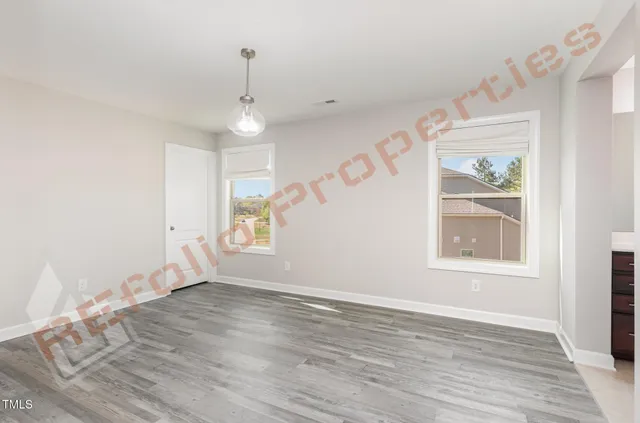 an empty room with wooden floor chandelier fan and windows