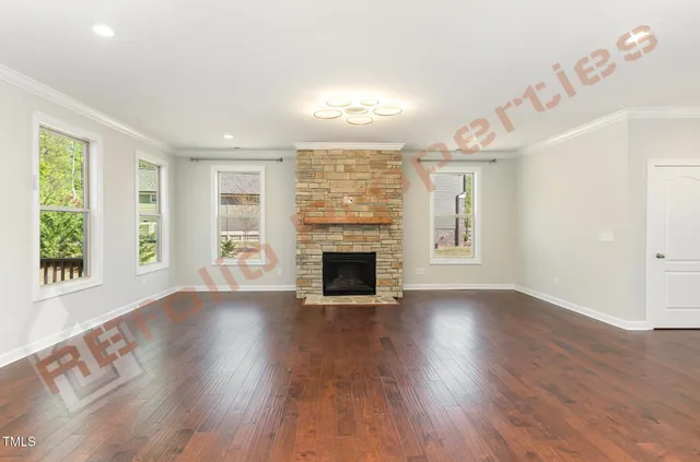 an empty room with wooden floor fireplace and windows