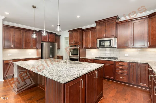 a kitchen with kitchen island granite countertop wooden cabinets a center island a stove and a wooden floors