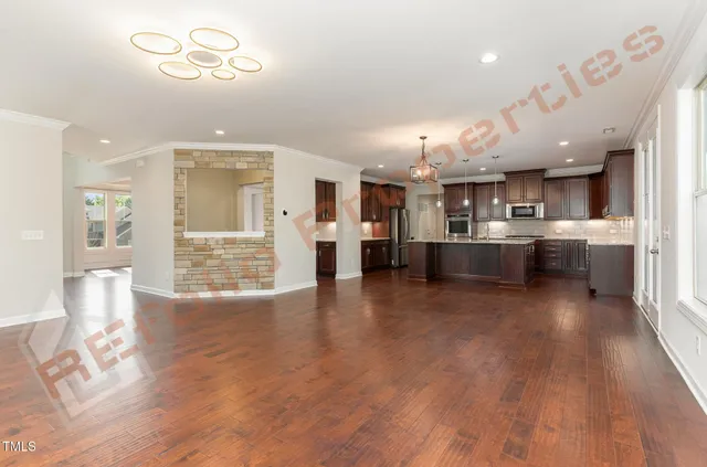 a living room with stainless steel appliances kitchen island granite countertop a wooden floor and a view of kitchen