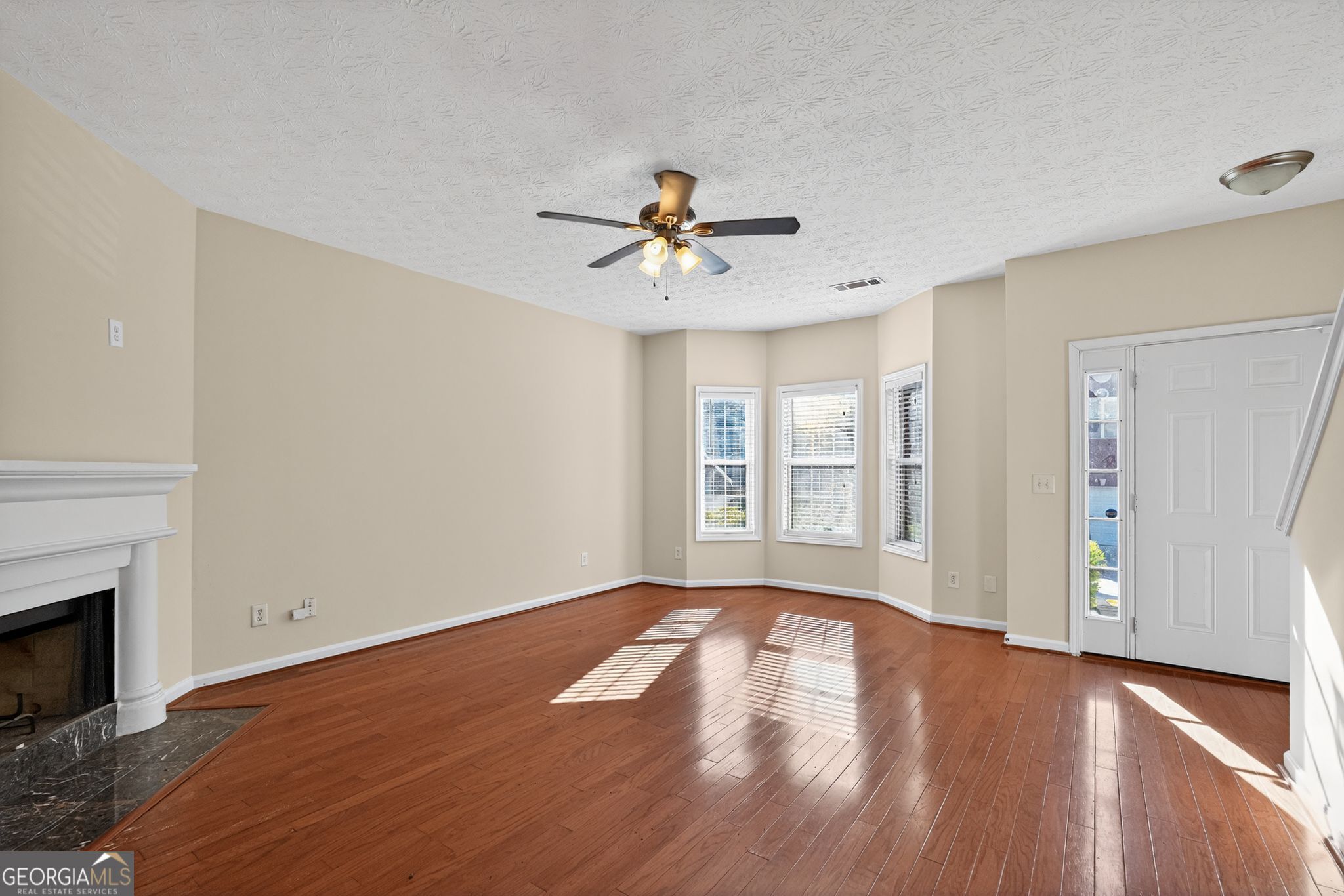 3812 Walnut Path Lithonia, GA 30038 - Photo 13 of 37 a view of a room with a ceiling fan a fireplace and wooden floor