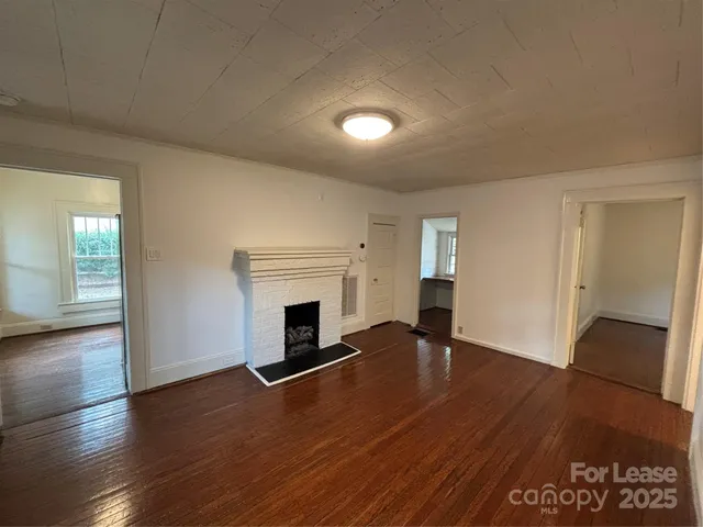 a view of empty room with wooden floor and fireplace