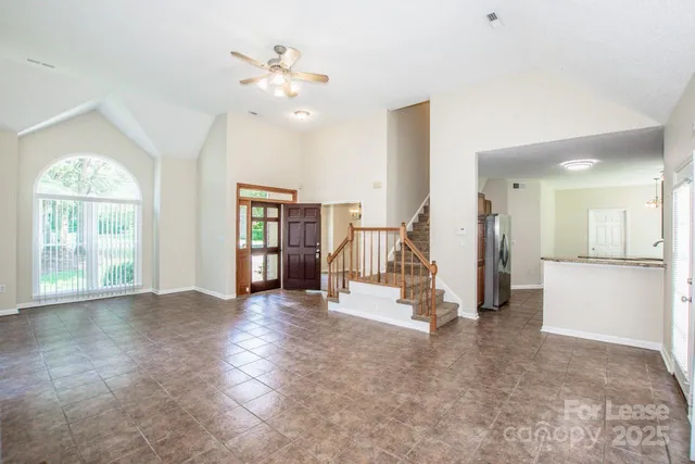 a view of an empty room with window and a kitchen