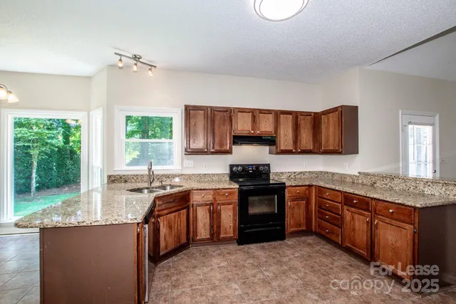 a kitchen with stainless steel appliances granite countertop sink stove top oven and cabinets