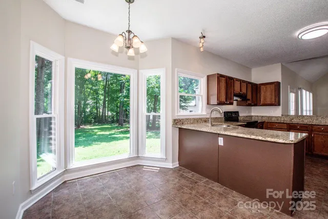 a kitchen with kitchen island granite countertop a stove a sink dishwasher a refrigerator with a dining table and chairs