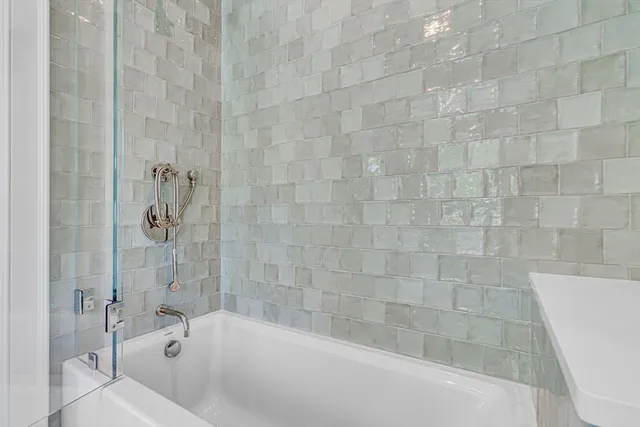 a bathroom with a granite countertop sink a mirror a bathtub and shower