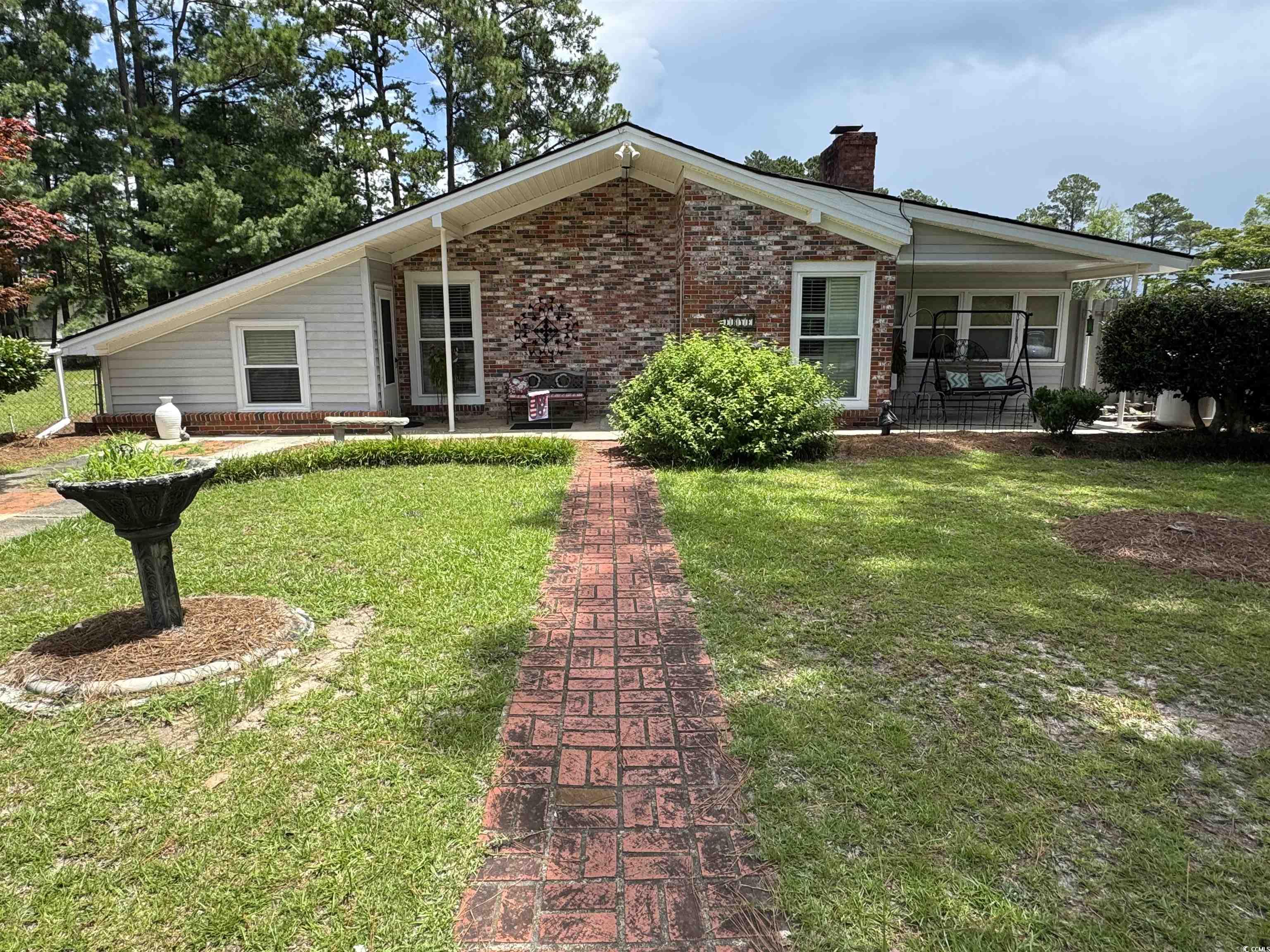 View of front of property featuring brick siding, a front lawn, and a chimney