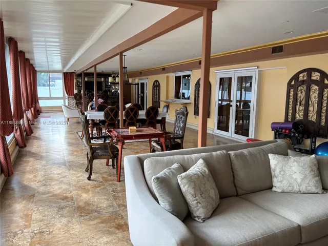 a living room with furniture a flat screen tv and floor to ceiling window