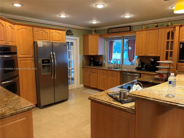 a kitchen with stainless steel appliances granite countertop a refrigerator a sink a stove top oven and a refrigerator with wooden floor